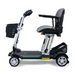 The Golden Technologies Portable Buzzaround GB120 Carry-On Travel Scooter is a sleek, black mobility scooter equipped with a cushioned seat, armrests, and a front basket. This ultra-portable model boasts four wheels and a fold-flat design for convenient transport, powered by a reliable lithium-ion battery.