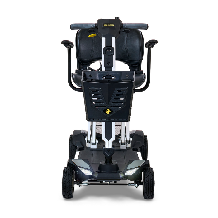 The Golden Technologies Portable Buzzaround GB120 Carry-On Travel Scooter is a compact, ultra-portable four-wheel mobility scooter in black and white. It features a comfortable seat, handlebar, and streamlined design with the manufacturer's logo on the front panel. Powered by a lithium-ion battery, it offers efficient travel for users.