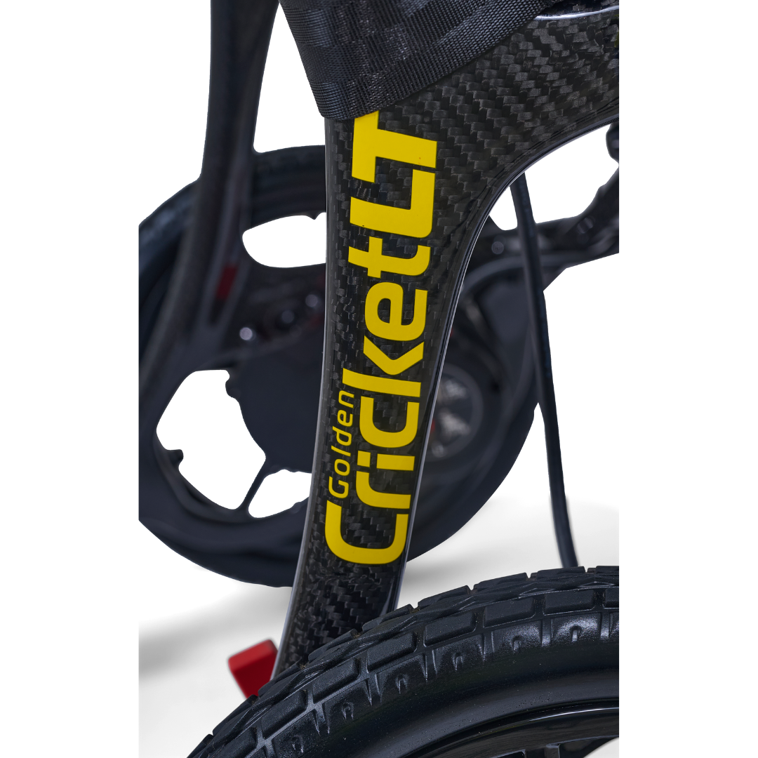 Close-up of the black Golden Cricket™ LT Carbon Portable Lightweight Powerchair (only 25 lbs), focusing on the front wheel, detailed tread, and fork against a white background—highlighting its spirit of exceptional freedom.
