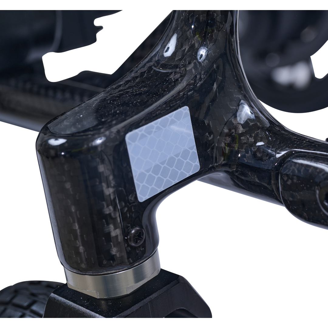 Close-up of the Golden Cricket™ LT Carbon Portable Lightweight Powerchair's glossy carbon fiber frame, featuring a small reflective hex-pattern sticker, highlighting its ultra-light 25 lb design for exceptional portability and freedom.