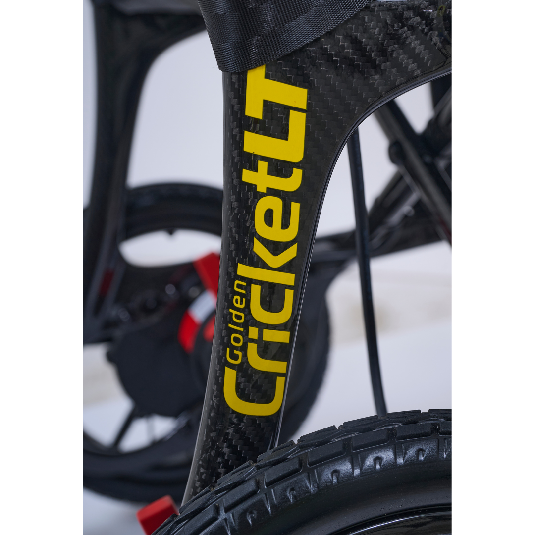 Close-up of the Golden Cricket™ LT Carbon Portable Lightweight Powerchair in sleek black and yellow. The image highlights the tire and wheel, showcasing the exceptional freedom and performance of this 25 lb carbon powerchair.