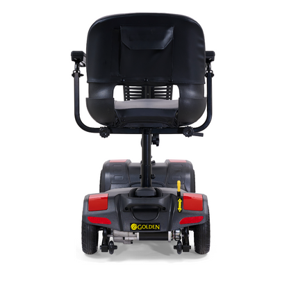 Rear view of the Golden Tech GB108 Buzzaround LT 4-Wheel Mobility Scooter in black, showing a lightweight stadium-style seat with cushion, backrest pocket, armrests, four wheels, red reflectors; supports up to 300 lb.