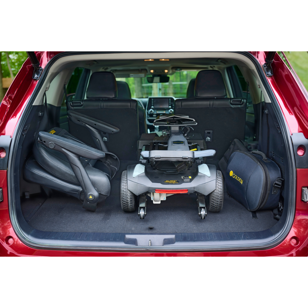 A red SUV trunk is open, showing a Golden Buzzaround GB220 CarryOn HD Travel Scooter with a 400 lb weight capacity, folded seat, and black carrying bag—all neatly arranged in the spacious cargo area.