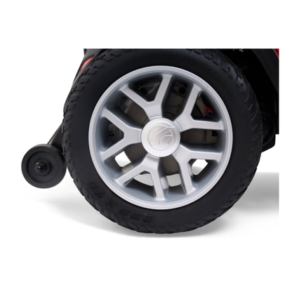 Close-up of a large black rubber wheel with a silver hubcap, like those on the Golden Tech BuzzAbout Portable Power Wheelchair, and a small stabilizing caster behind it. "9 x 2.75" tread markings are visible against a white background.