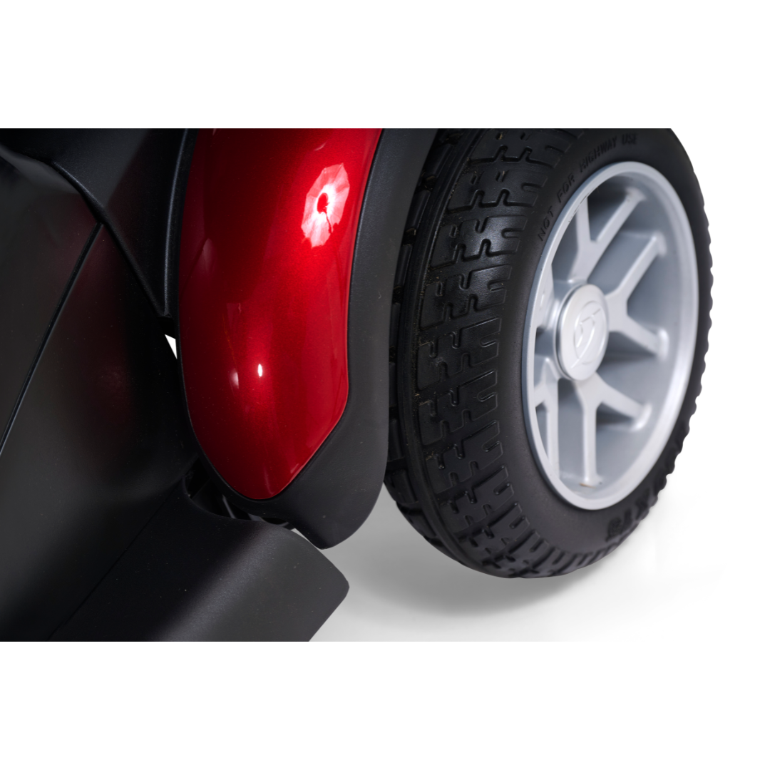 Close-up of a Golden Tech BuzzAbout Portable Power Wheelchair’s rear wheel with a silver rim and textured black tire beside a shiny red fender—ideal for BuzzAbout users or similar portable power wheelchairs.