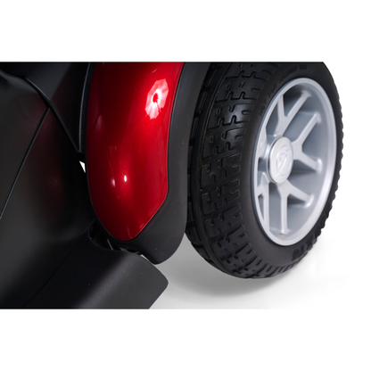 Close-up of a Golden Tech BuzzAbout Portable Power Wheelchair’s rear wheel with a silver rim and textured black tire beside a shiny red fender—ideal for BuzzAbout users or similar portable power wheelchairs.