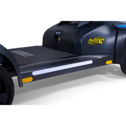 Close-up of the footrest on the Golden Tech Buzzaround GB152 XL+ 4-Wheel Mobility Scooter, featuring a textured surface, yellow reflectors, and the Buzzaround logo on its sleek black frame.