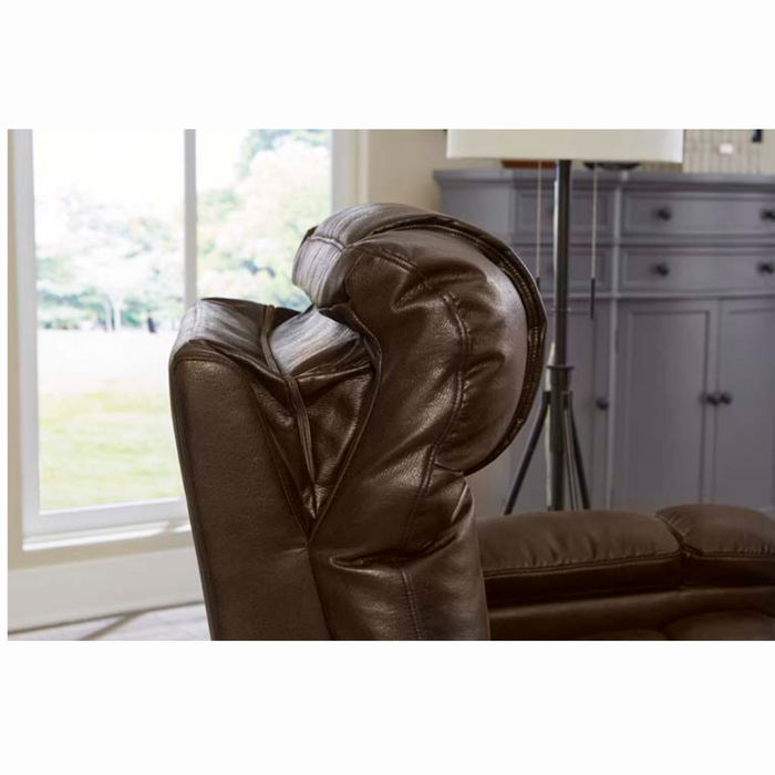 A close-up of the brown Golden Tech Rhea PR442 MaxiComfort Recliner with adjustable headrest, USB port, and 4-Zone Comfort technology by a window. A gray cabinet and white lamp in the background complete the modern, cozy living room setting.