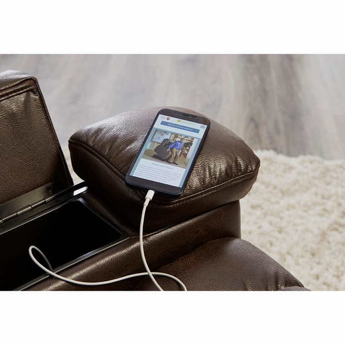 A smartphone is on the armrest of a soft brown Golden Tech Rhea PR442 MaxiComfort Recliner, connected via USB charging port. A light rug and classic wood floor enhance the cozy atmosphere.