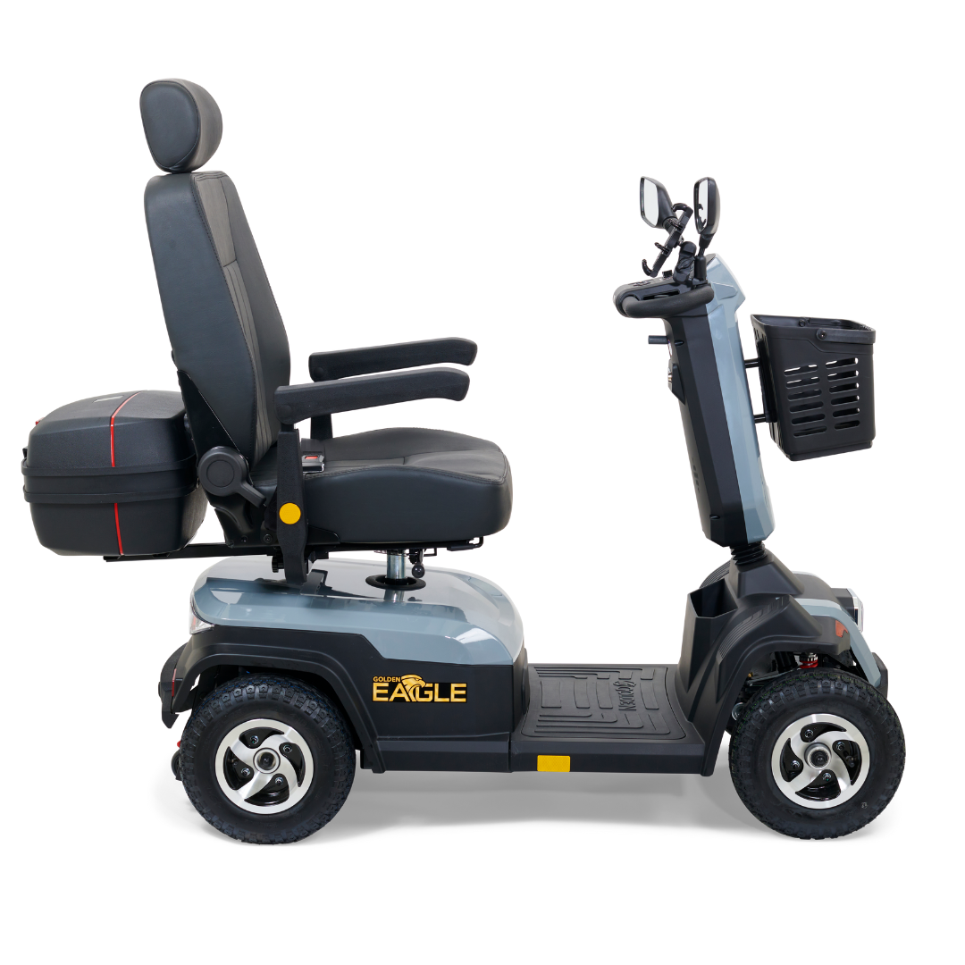 The Golden Tech Eagle HD Bariatric 4-Wheel Scooter with Suspension excels in off-road performance, featuring a padded seat, armrests, backrest, and four sturdy wheels. It includes a front basket, mirrors, and rear storage box for outdoor adventures. Available in gray.