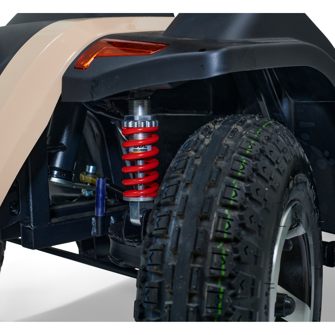 Close-up of the Golden Tech Eagle HD Bariatric 4-Wheel Scooters rear wheel and suspension system, showcasing a striking red coil spring shock absorber and black tire with tread patterns. Ready for adventure against a neutral light background.