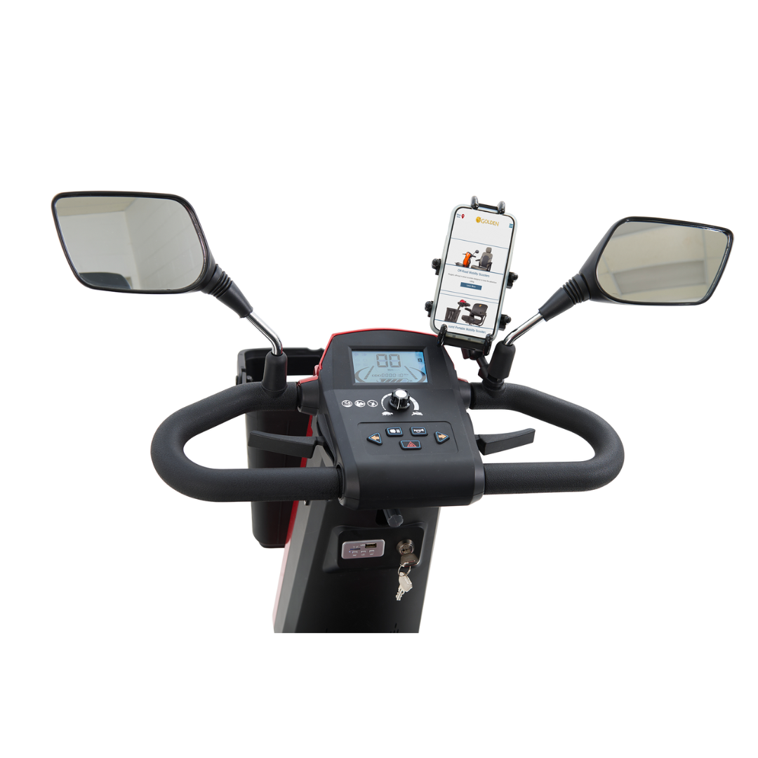 The image features the steering and control panel of a Golden Tech Eagle HD Bariatric 4-Wheel Scooter with Suspension, showcasing a digital display, control buttons, two rearview mirrors, and a smartphone holder displaying mobility-related content, highlighting its off-road capabilities.
