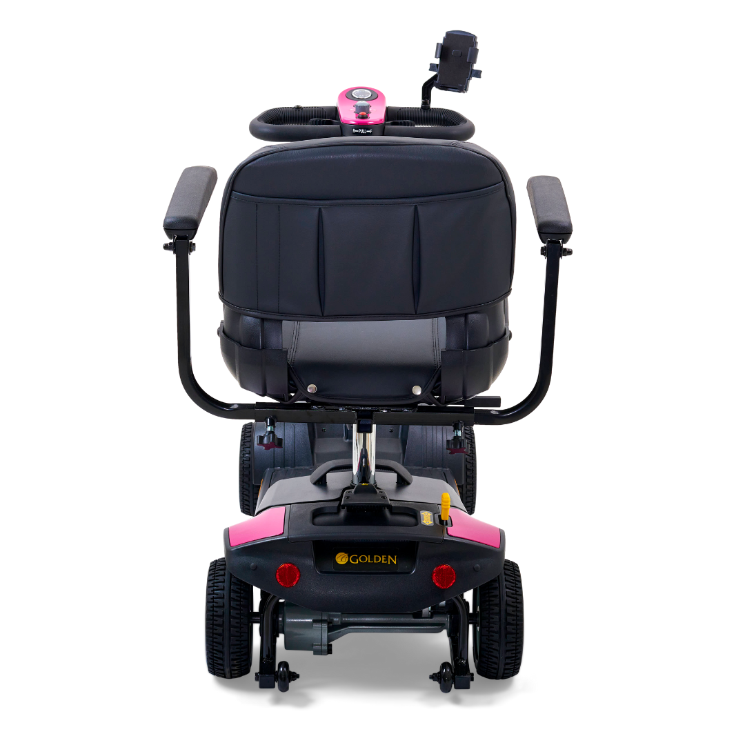 Rear view of the Golden Tech GB124 Buzzaround XL 4-Wheel Portable Mobility Scooter with a black seat and pink accents, featuring armrests, rear wheels, and accessory storage. Its black base showcases the logo near the wheels, emphasizing excellent maneuverability and optional extended range battery.