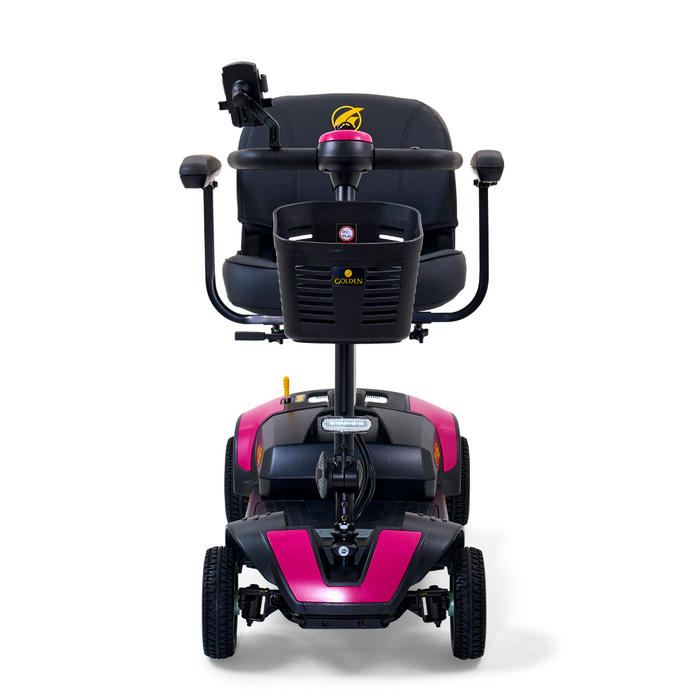 The front view of the Golden Tech GB124 Buzzaround XL 4-Wheel Portable Mobility Scooter showcases a pink and black design, extended range battery, cushioned black seat with armrests, a control tiller, and four wheels for enhanced maneuverability.
