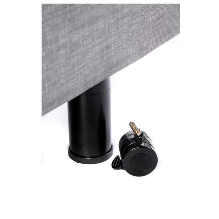 A black cylindrical bed leg from Golden Tech Passport stands upright, attached to gray upholstered furniture for safety and functionality, while a similarly colored caster wheel lies on its side, exemplifying high-quality homecare bed accessories against a white background.