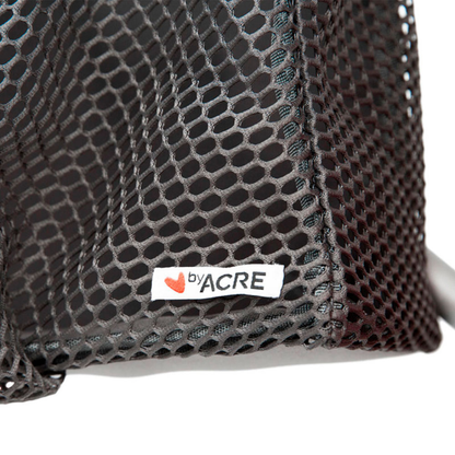 Close-up of black mesh fabric from the Grocery Bag for byACRE Carbon Fiber Rollators, featuring a small white label with a red heart—ideal as a stylish grocery or shopping bag for your rollator.