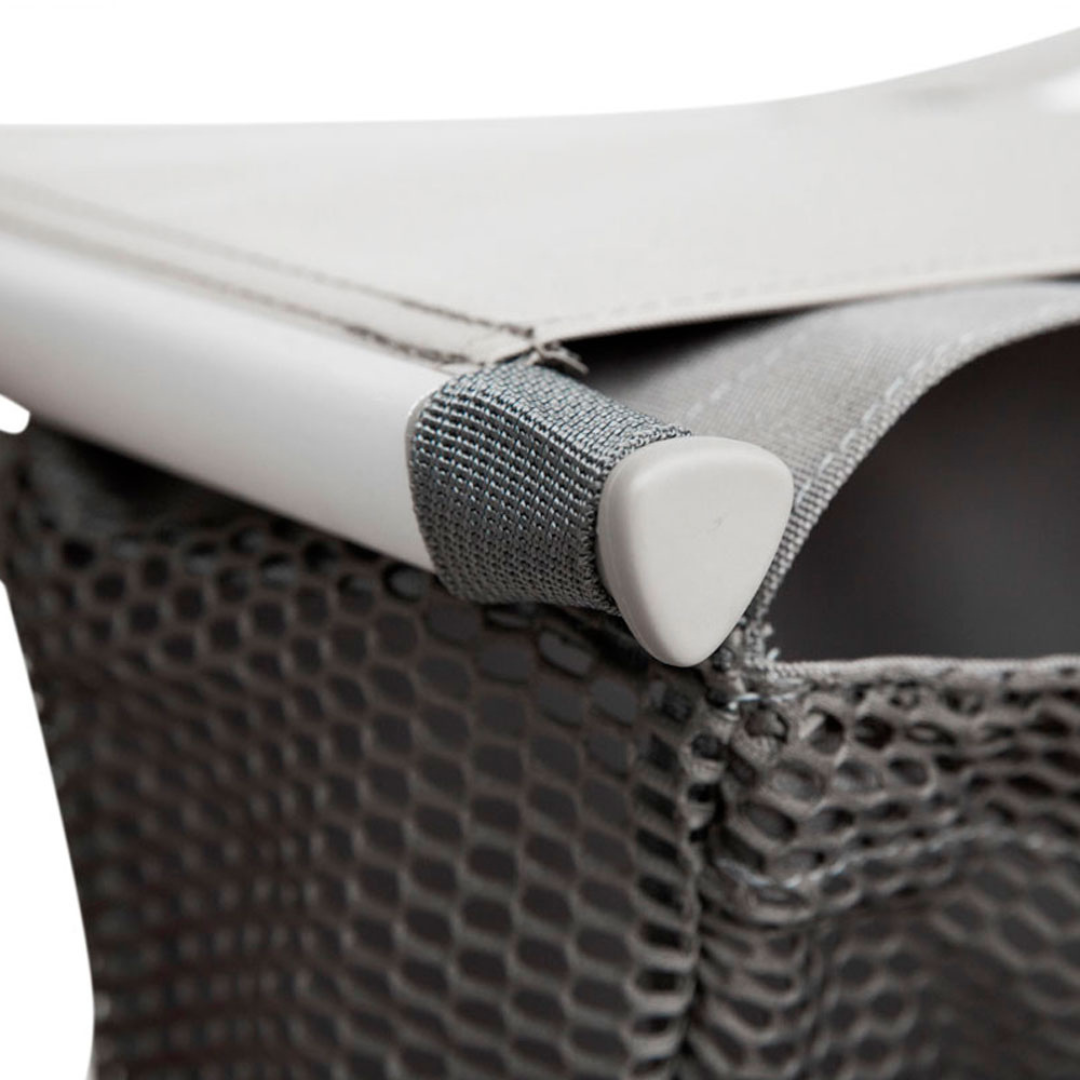 Close-up of a gray mesh Grocery Bag for byACRE Carbon Fiber Rollators, attached to a white metal frame and secured at the corner with a fabric strap.