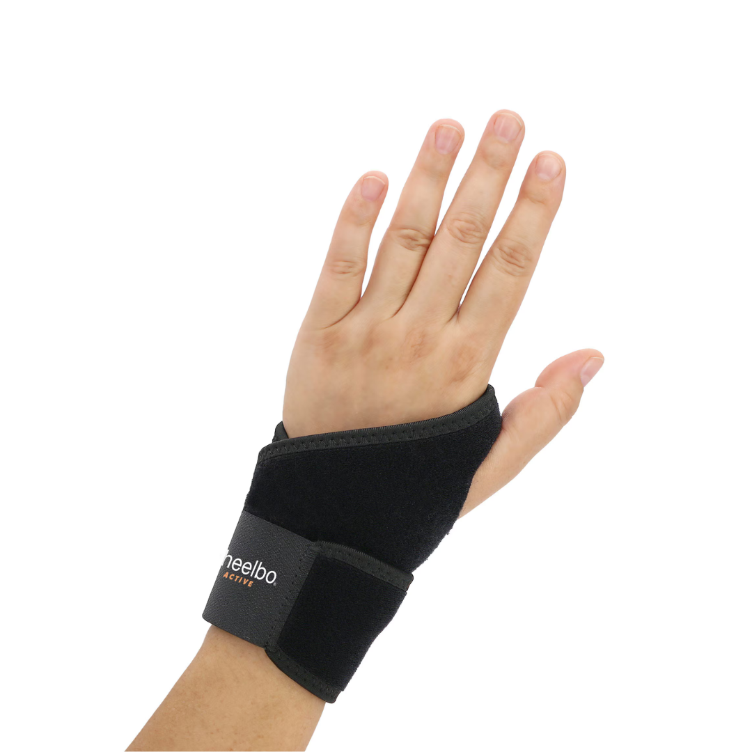 A left hand wears the Heelbo® Universal Support Wrist Compression Brace in black with a Velcro strap for wrist pain relief, fingers spread and palm facing forward, shown against a white background.