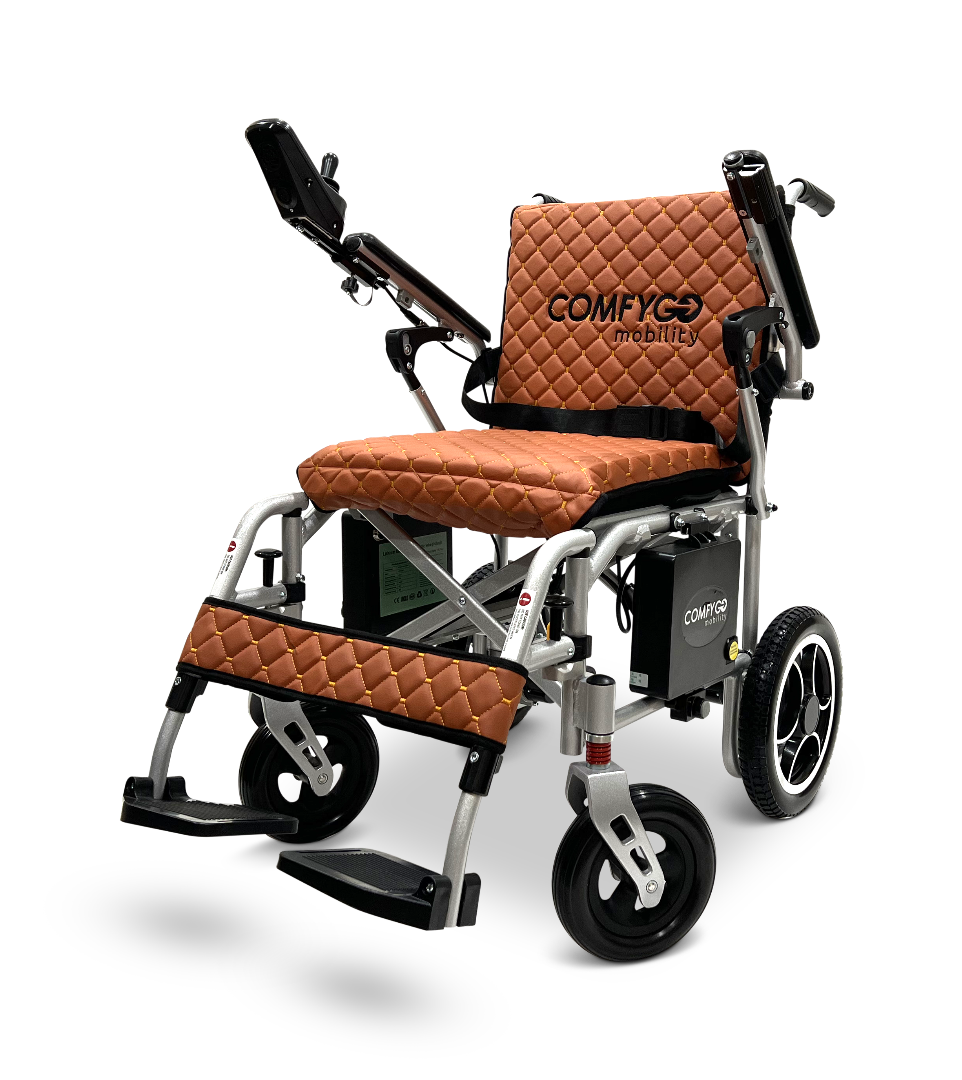 The ComfyGo X-7, a 40-lb lightweight foldable electric wheelchair, features quilted brown upholstery on the seat, backrest, and leg supports. It has foldable armrests, a right-side control panel, and large rear wheels for easy maneuverability.