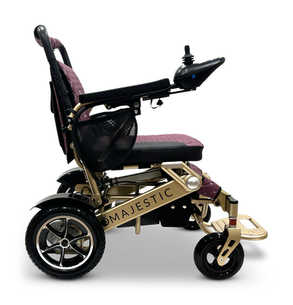 Side view of the MAJESTIC IQ-7000 Remote Controlled Electric Wheelchair, showcasing its gold metallic frame and maroon cushioning. The wheelchair is equipped with a 360-degree joystick on the armrest and black wheels, enhancing its lightweight design for easy mobility.