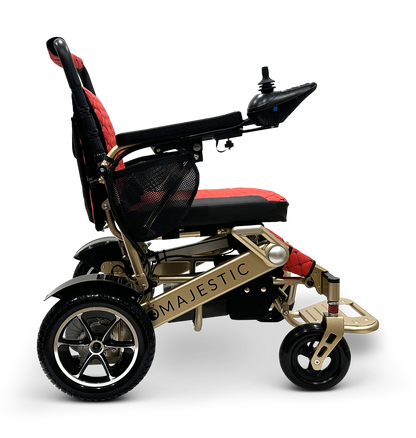 The MAJESTIC IQ-7000 showcases a side view in gold and black with a red cushion. It features a comfortable seat, 360-degree joystick control on the armrest, Majestic on the side, and sturdy wheels designed for enhanced mobility.
