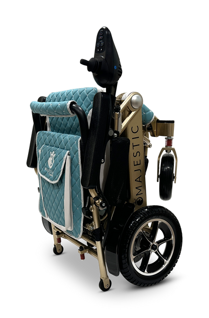 The MAJESTIC IQ-7000 is a blue and gold auto-folding electric wheelchair featuring quilted fabric, a lightweight black frame with silver accents, a 360-degree joystick on the armrest, and a back storage pouch. Its black tires have silver rims.