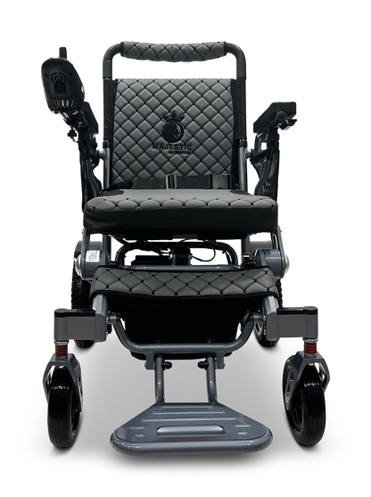 The MAJESTIC IQ-7000 Remote Controlled Electric Wheelchair is sleek and black with diamond-patterned upholstery. It features MAJESTIC branding on the backrest, a 360-degree joystick control on the right armrest, and a sturdy footrest for easy maneuverability.