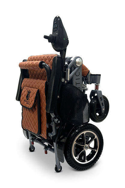 The MAJESTIC IQ-7000 is a folded mobility scooter with brown quilted fabric, a 360-degree joystick, and black wheels. It features a metallic frame with a side storage pocket, delivering a sleek design perfect against the black background.