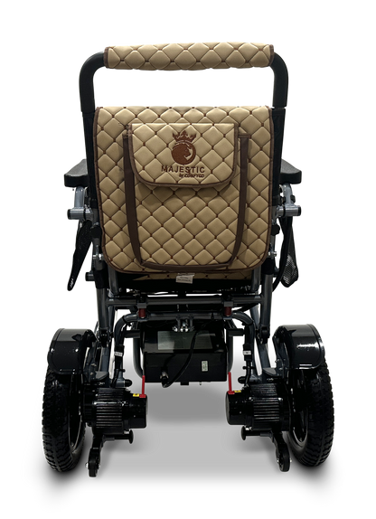 The MAJESTIC IQ-7000 is a lightweight folding electric wheelchair with a quilted brown seat and bag, featuring the Majestic logo. It has a black frame with exposed wheels and mechanical parts, plus a 360-degree joystick for easy control.