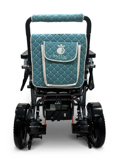 The rear view of the MAJESTIC IQ-7000 reveals a lightweight, auto-folding electric wheelchair with a quilted teal backrest cover. It features white stitching, trim, and a Majestic unicorn logo. A 360-degree joystick enhances its design, while large wheels with thick treads ensure smooth mobility.