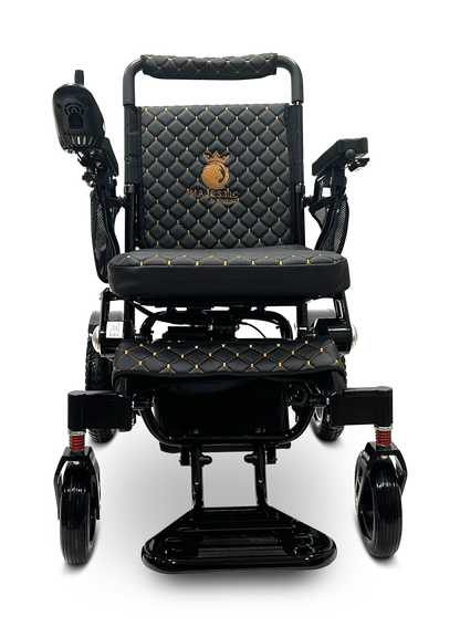 The MAJESTIC IQ-7000 Remote Controlled Electric Wheelchair is a stylish and lightweight model featuring black upholstery with gold stitching and a quilted pattern. It includes auto-folding capabilities, armrests, sleek wheels, and an intelligent joystick positioned on the left side. The backrest is adorned with an emblem that reads "Majestic.