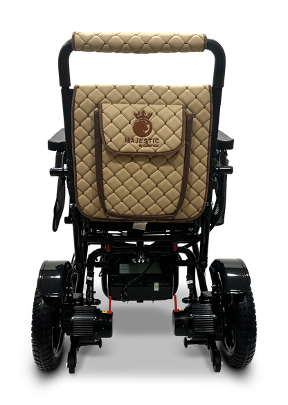 The rear view of the MAJESTIC IQ-7000 Remote Controlled Electric Wheelchair highlights its quilted tan and brown backrest, which prominently displays a logo featuring the word "Majestic" beneath a crown emblem. This lightweight wheelchair is equipped with an intelligent joystick, black accents, and large wheels.