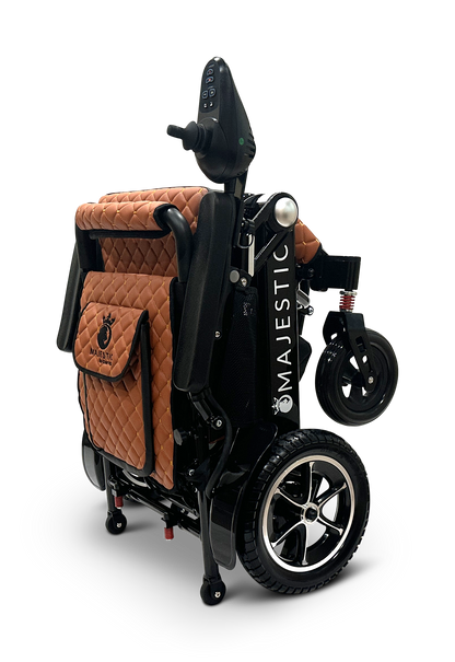The MAJESTIC IQ-7000 Remote Controlled Electric Wheelchair is designed with quilted brown leather upholstery and a sleek black frame. It features an intelligent joystick conveniently positioned on the armrest. The product's name, MAJESTIC, embellishes the side, while its two small front wheels and larger rear wheels provide smooth mobility.