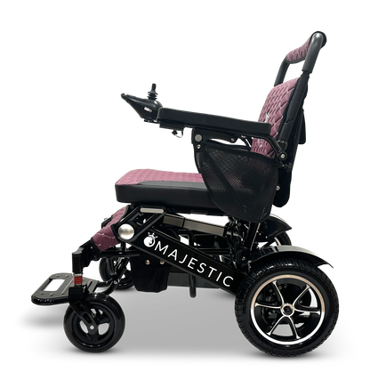 Introducing the MAJESTIC IQ-7000: a sleek black, lightweight electric wheelchair featuring a quilted pink seat and backrest. It is equipped with an intelligent joystick control on the right armrest, a black mesh side pocket, and durable wheels. The name "Majestic" is elegantly printed on the side.