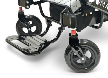 Close-up of the footrest and front wheels of a Remote Controlled Electric Wheelchair, MAJESTIC IQ-7000, on a white background. The black metallic footrest, accented by two small wheels attached to black suspension forks, highlights the sleek design of this lightweight wheelchair.