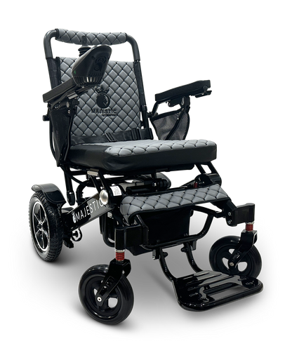 Introducing the MAJESTIC IQ-7000 Remote Controlled Electric Wheelchair, featuring a sleek black design with quilted upholstery, armrests, and joystick control. Proudly displaying the Majestic branding on the side, this lightweight model comes with sturdy wheels and a foldable footrest, elegantly set against a crisp white background.