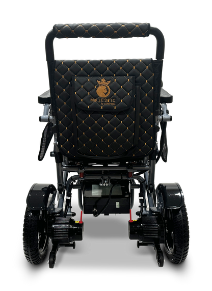 The MAJESTIC IQ-7000 remote-controlled electric wheelchair features a black quilted pattern with gold stitching and displays MAJESTIC on the seat back. It has durable wheels, a 360-degree joystick, and is set against a plain backdrop.