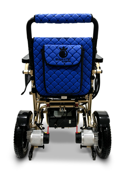 Rear view of the MAJESTIC IQ-7000 Remote Controlled Electric Wheelchair, designed with a sophisticated quilted blue seat cushion and backrest. Its elegant metallic frame highlights two robust rear wheels and motors. The back pocket proudly displays the MAJESTIC branding, merging style and convenience in this foldable wheelchair.