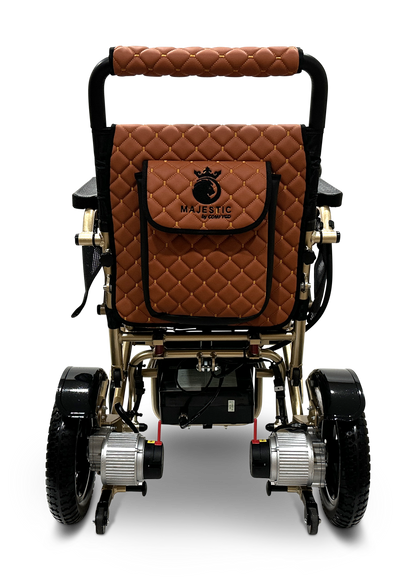 The MAJESTIC IQ-7000 Auto Folding Electric Wheelchair is showcased from the rear, featuring a luxurious brown quilted design, large back pocket with Majestic, black and gold accents, small motors under the seat, thick tires, and a 360-degree joystick for smooth operation.