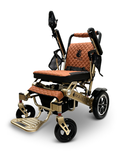 The MAJESTIC IQ-7000 is a luxury folding electric wheelchair featuring a gold frame and brown quilted seat, large rear wheels, 360-degree joystick for easy navigation, and armrest controls. The word Majestic adorns the frame.