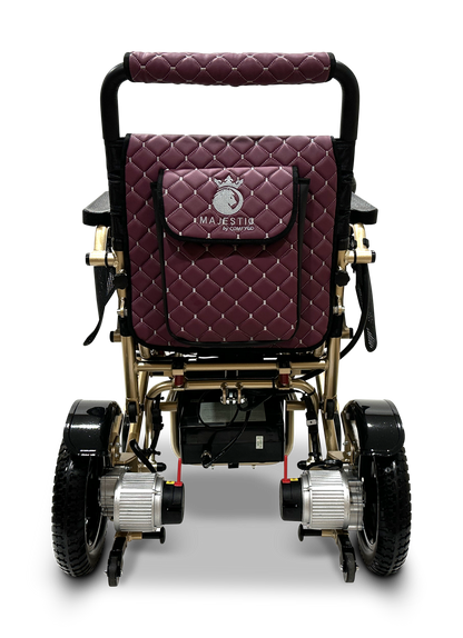 Introducing the MAJESTIC IQ-7000 Remote Controlled Electric Wheelchair, a lightweight, luxurious model with a deep red quilt and golden frame accents. Designed for both comfort and style, it features sturdy black wheels and proudly displays the Majestic brand name on the back, making it an elegant yet practical choice for various settings.