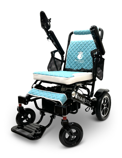 The MAJESTIC IQ-7000 Auto Folding Remote Controlled Electric Wheelchair is designed in black with blue quilted cushions and armrests. It includes an intelligent joystick control on the right armrest, sturdy wheels, and an auto folding footrest. The brand name Majestic is prominently displayed on the chair.