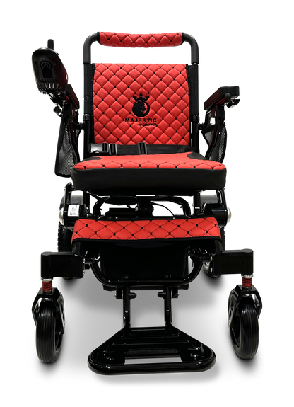 The MAJESTIC IQ-7000 Remote Controlled Electric Wheelchair is available in red and black, boasting quilted upholstery with armrests. The backrest prominently features the MAJESTIC logo. This folding wheelchair blends a lightweight design with wheels engineered for superior stability and mobility.