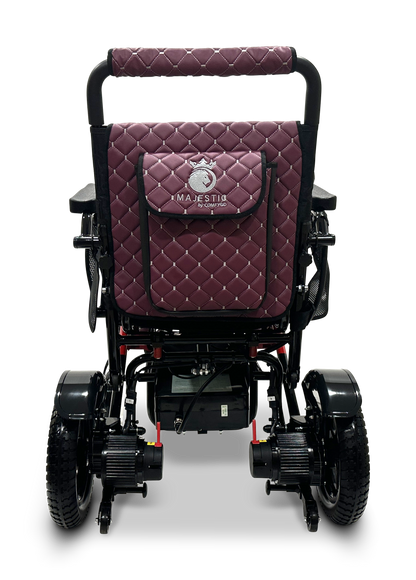 A maroon, quilted MAJESTIC IQ-7000 Remote Controlled Electric Wheelchair is pictured from the back, with its brand name MAJESTIC embroidered on a pocket. This lightweight design features auto-folding capabilities, black armrests, and large rear wheels for easy mobility.