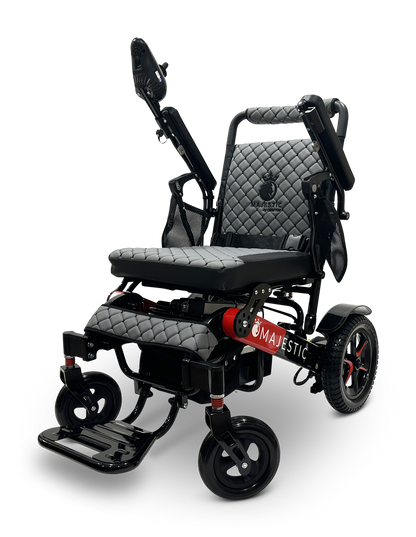 The MAJESTIC IQ-7000 Remote Controlled Electric Wheelchair features a sleek black design with quilted padding, adjustable armrests and footrests, and a lightweight structure. It also includes auto-folding capabilities with the Majestic logo on the side, red accents, and large wheels perfect for both indoor and outdoor use.