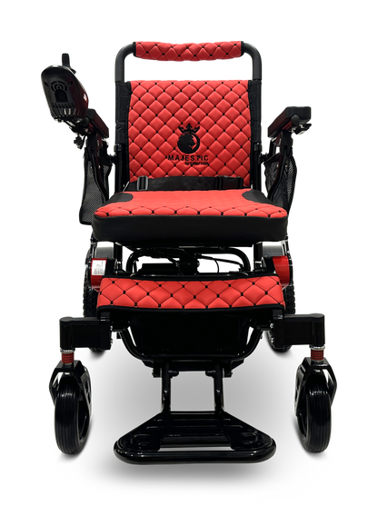 The MAJESTIC IQ-7000 Remote Controlled Electric Wheelchair in red and black boasts quilted upholstery and features an intelligent joystick for seamless control. Its design is highlighted by a logo on the backrest and armrests, complemented by large rear wheels for enhanced stability.
