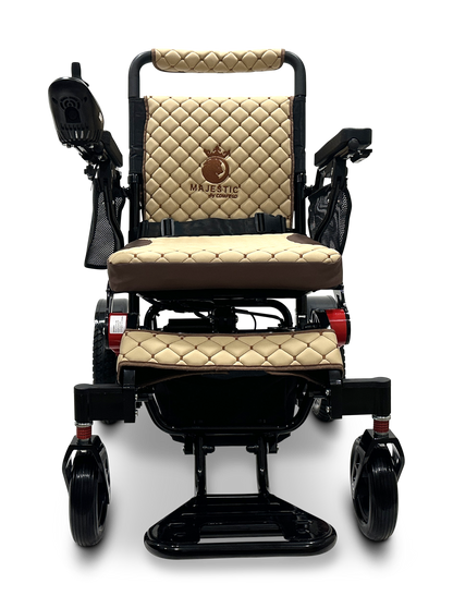 Discover the sophistication of the MAJESTIC IQ-7000 Remote Controlled Electric Wheelchair, featuring a luxurious beige and black design with quilted upholstery and armrests. The backrest highlights an embroidered "Majestic" emblem, while the lightweight model includes an intelligent joystick on the right armrest and a convenient footrest below.