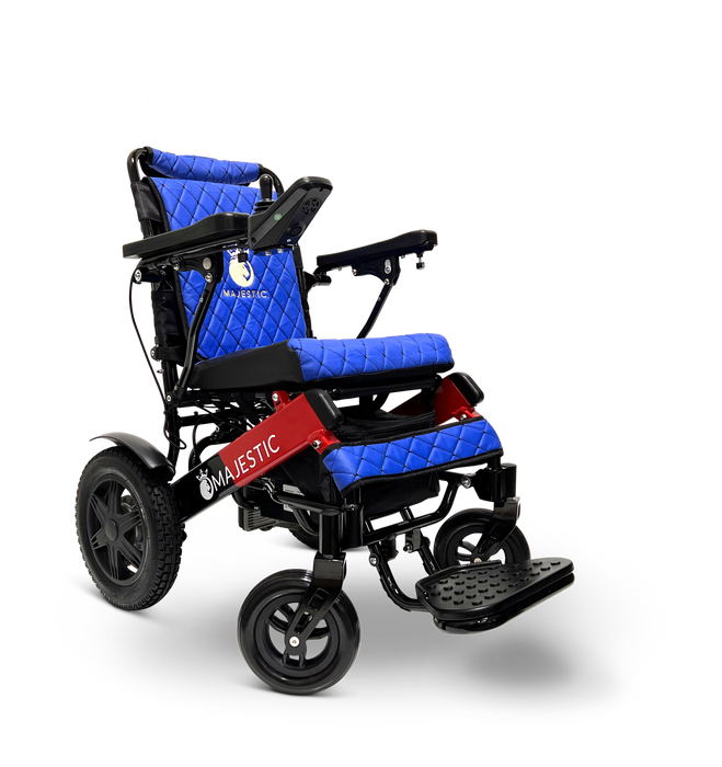 The ComfyGo MAJESTIC IQ-9000 Remote Controlled Electric Wheelchair is a blue and black model with a quilted design. It includes armrests, large rear wheels, smaller front wheels, a footrest, and a joystick controller on the right armrest. The Majestic brand name is prominently displayed on the backrest and base.