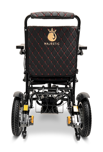 The ComfyGo MAJESTIC IQ-9000 Auto Reclining Electric Wheelchair is shown from the back, featuring black quilted upholstery with red stitching, a gold Majestic logo, and large rear wheels—all made with durable aircraft-grade aluminum alloy.