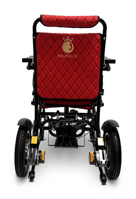 The rear view of the ComfyGo MAJESTIC IQ-9000 Auto Folding Electric Wheelchair reveals a red seat with a black frame, highlighted by quilted fabric and adorned with a gold crown logo featuring the word "Majestic" embroidered underneath. It is equipped with brushless silent motors, enhancing its sleek design, which includes wheels and footrests for smooth mobility.